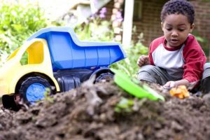 1 child playing with toy truck in the garden