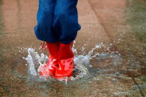 1 child with red boots jumping in puddle