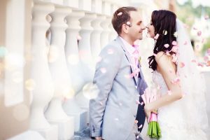 1 bride and groom smiling surrounded by rose petals