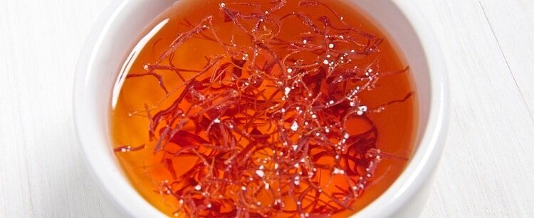Pieces of saffran floating in orange tea