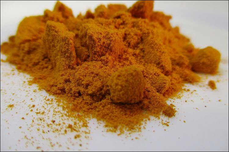Turmeric powder placed on a white surface