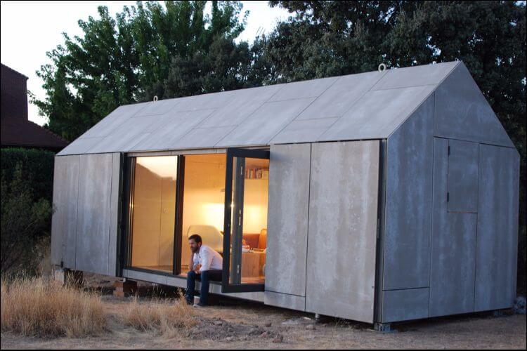 Minimalist studio shed, with simple beige walls, placed on the ground in front of trees