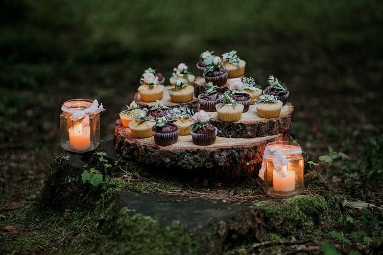 Cupcakes on a stump with candles and moss nearby