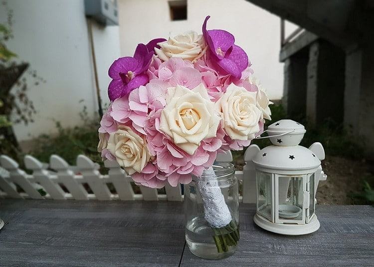 Wedding flowers in purple, pink, and white hues, placed in a jar